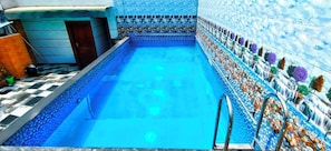 A swimming pool with a tiled border and a ladder. - HOTEL The Rich Grand (Agra)