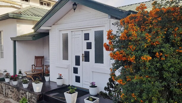 Une maison à deux étages avec un balcon, des plantes en pot et une chaise en bois.