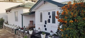 Ein zweistöckiges Haus mit einem Balkon, Blumentöpfen und einem Holzstuhl.