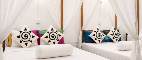 A room with two beds, each with a canopy and decorative pillows.