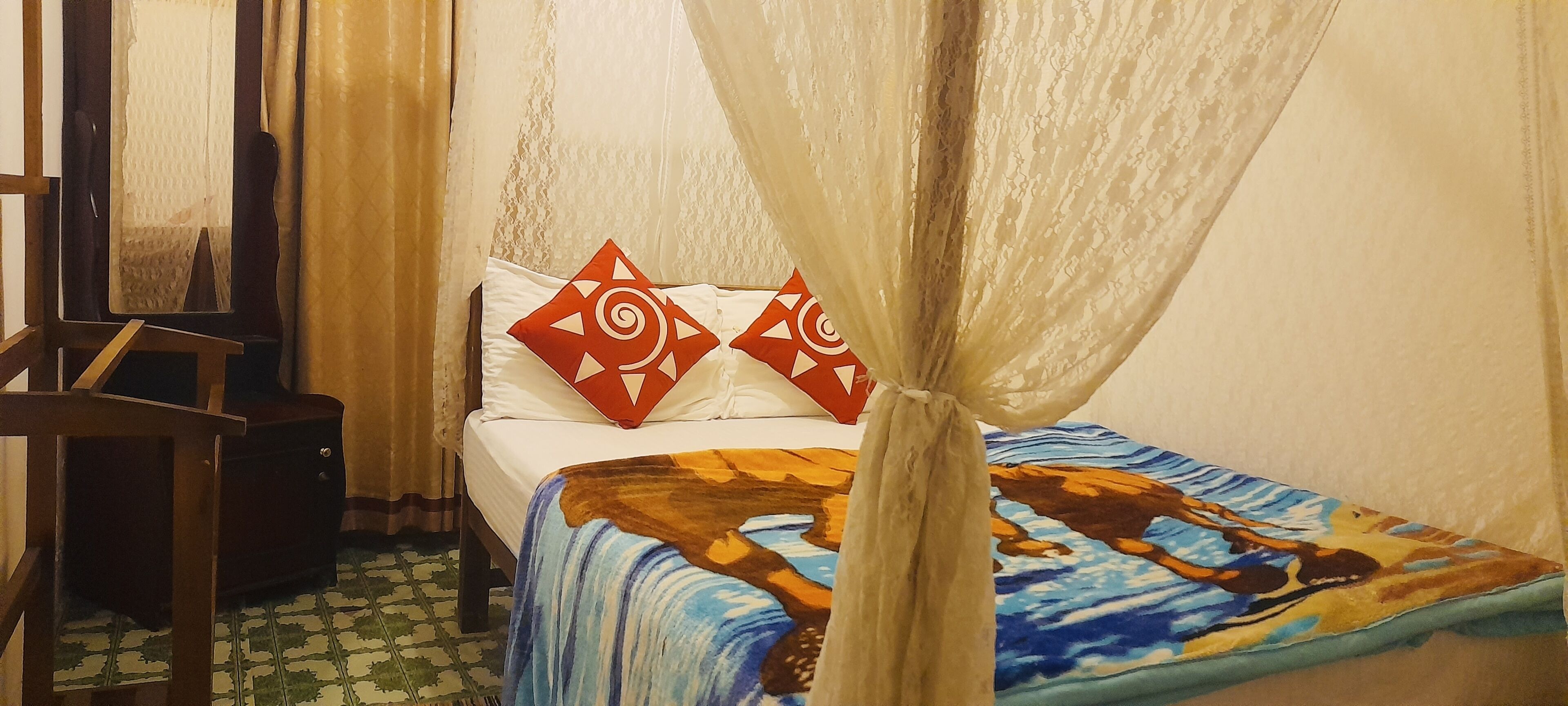 A room with a bed, a chair, a small table, and a curtain.