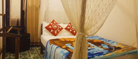 A room with a bed, a chair, a small table, and a curtain.