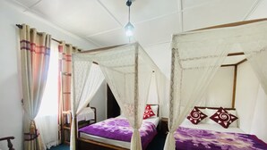 Une chambre avec deux lits, chacun doté d’un baldaquin, et une chaise en bois.