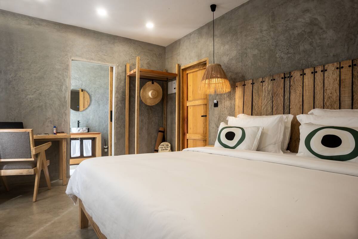 Un dormitorio con cama, escritorio, silla, lámpara colgante y cabecera de madera.