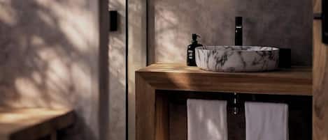 A modern bathroom with a wooden vanity, a round mirror, and two white towels.