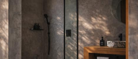 Un baño moderno con cabina de ducha de vidrio, tocador de madera y lavamanos de mármol.