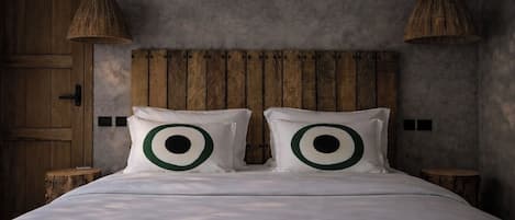 Un letto con testiera in legno, due lampade ai comodini e due cuscini con motivi circolari.