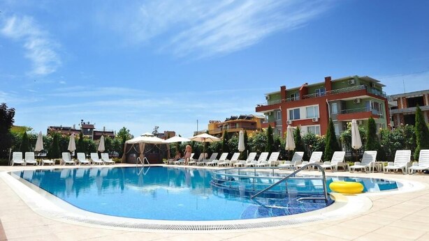 Une piscine entourée d’immeubles à plusieurs étages, avec des chaises longues et des parasols.