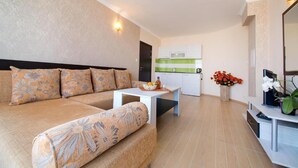 Un salon moderne avec un canapé, une petite table et un coin cuisine à l’arrière-plan.