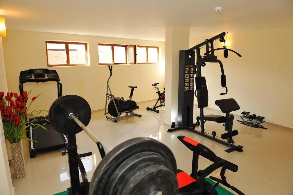 A home gym with a treadmill, stationary bike, weight bench, and various exercise equipment.