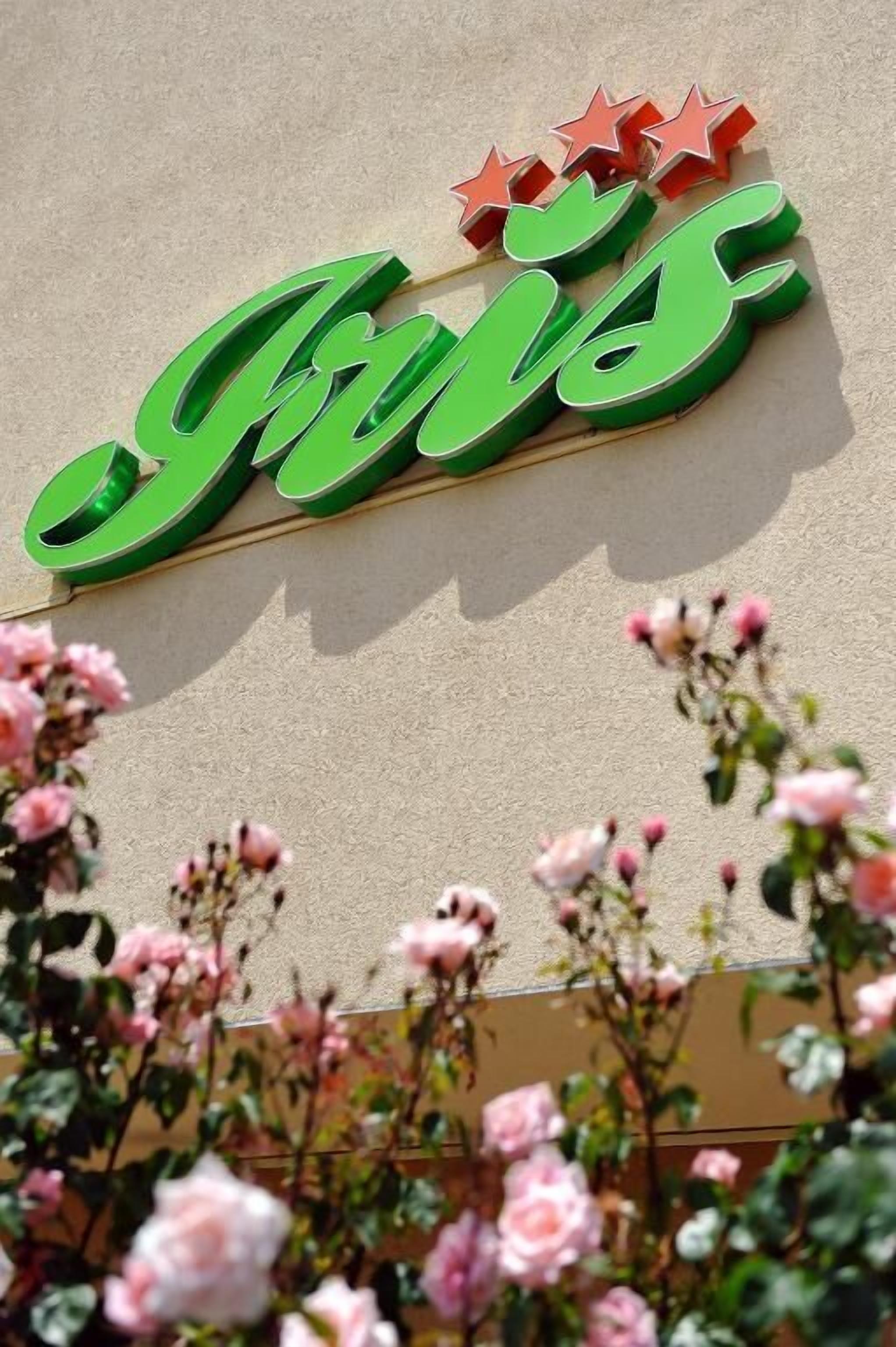 A building with a green sign that reads "Jus" and three red stars above it.
