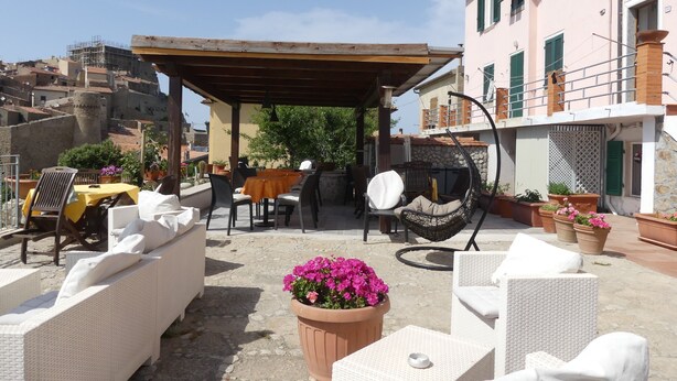 Une terrasse extérieure avec des meubles en osier, un espace salon couvert et des plantes en pot.