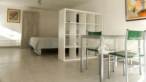 Une pièce comprenant un lit, une étagère blanche, une chaise verte et un tableau encadré accroché au mur.