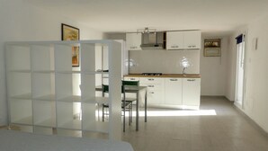 Une cuisine moderne et bien éclairée, avec des meubles blancs, un coin repas comprenant une table et des chaises, et une grande fenêtre laissant entrer la lumière naturelle.