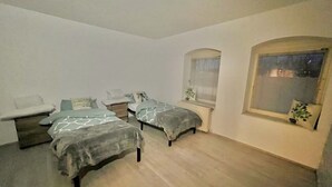 Una camera da letto piccola e luminosa con due letti, un comodino, una sedia e una finestra con vista.