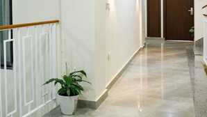 A hallway with a potted plant, white walls, and a wooden door at the end. - Sangam City Hotel (Kathmandu)
