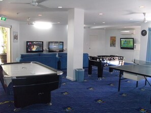 Enjoy games and entertainment in this room with a pool table, foosball table, and two flat-screen TVs.