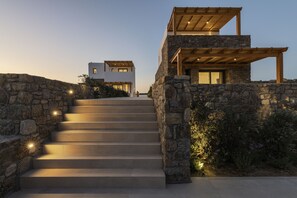A modern house with a stone facade, a wooden staircase, and a flat roof.