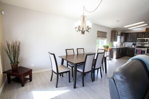 A dining area with a table and chairs, a chandelier, and a potted plant.