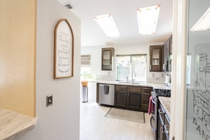 A modern kitchen with dark cabinets, a stainless steel sink, and a window providing natural light.
