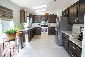 A modern kitchen with dark wood cabinets, stainless steel appliances, and a central island.