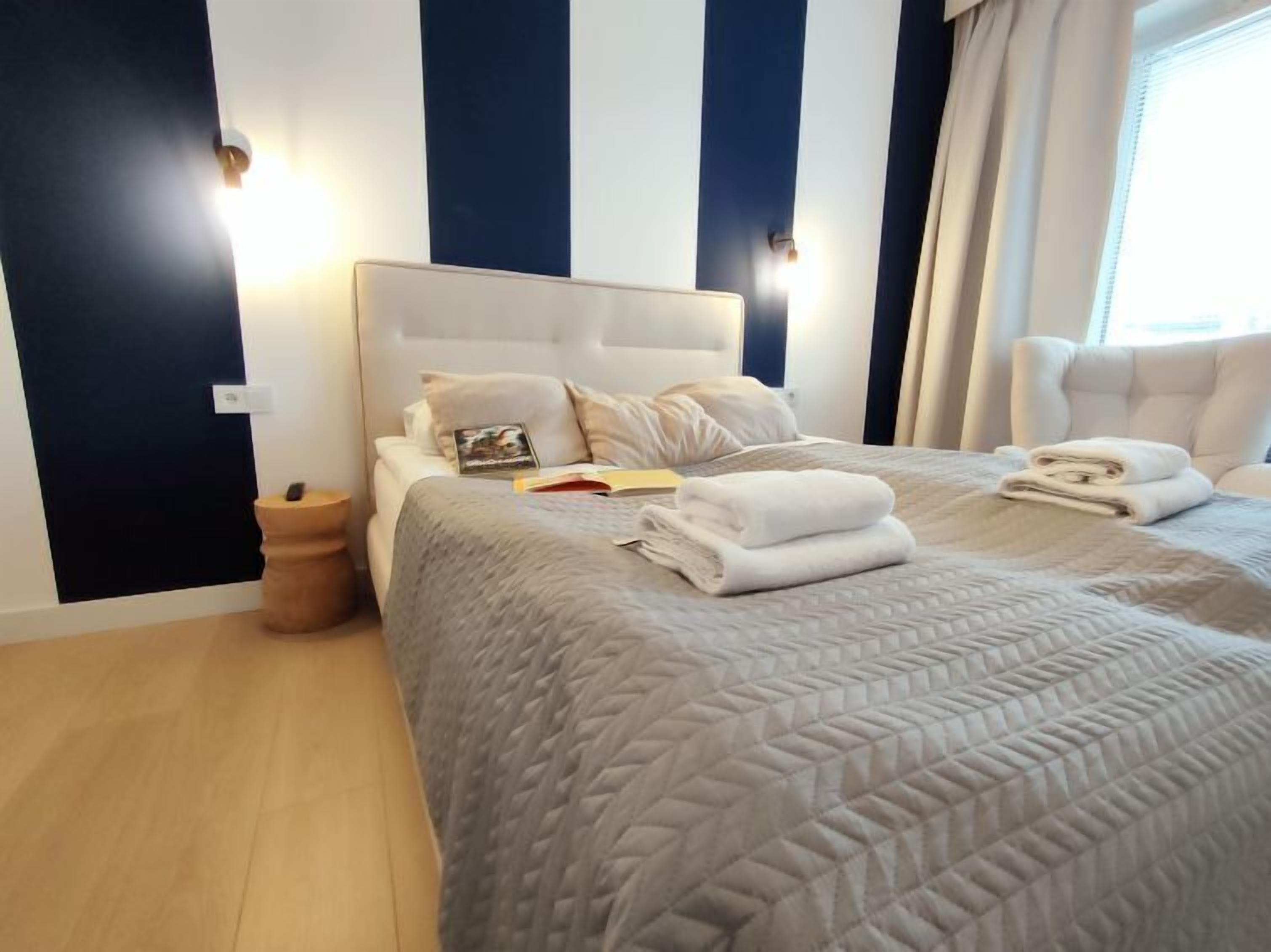 A neatly made bed with a quilted cover, pillows, and folded towels on a headboard.