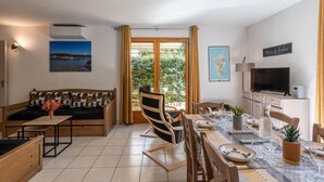 A modern living room with a sofa, dining table, chairs, and a TV. - Chez Béatrice et Pascal by Interhome (Lozari)