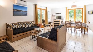 A modern living room with a sofa, a coffee table, and a dining area with chairs and a table. - Chez Béatrice et Pascal by Interhome (Lozari)
