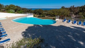 A swimming pool with lounge chairs, surrounded by a tiled deck and a view of the sea. - Chez Béatrice et Pascal by Interhome (Lozari)