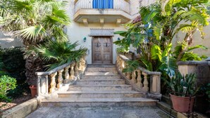 A stone staircase leading to a wooden door with a balcony above. - Villa Serenity B&b (Sannat)