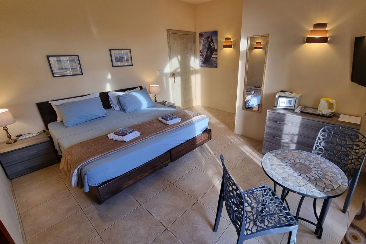 A hotel room with a bed, bedside table, lamp, chair, desk, and a TV.