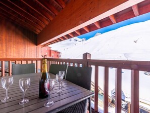 A wooden deck with a table and chairs, overlooking a snowy mountain. - Ecrin des Neiges (Val Claret) by Interhome (Tignes)