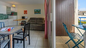 Een compacte leefruimte met kitchenette, een eethoek, een bank en een balkon met uitzicht.