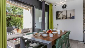 Un comedor con una mesa de madera, sillas verdes y una mesa baja de vidrio.
