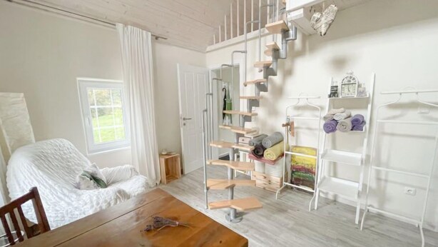 Une pièce comprenant un lit, une table en bois, une armoire blanche et une étagère murale blanche où sont posées des serviettes.