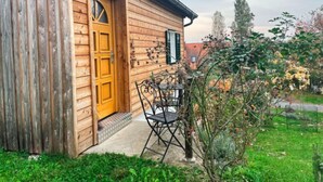 Une maison en bois avec une porte en bois et un petit porche doté d’une table et de chaises.