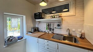 Une cuisine dotée de meubles en bois, d’un four à micro-ondes encastré, d’une fenêtre offrant une belle vue et de luminaires suspendus.