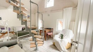 Une pièce compacte et moderne, dotée d’un lit en mezzanine, d’un coin repas et d’un escalier.