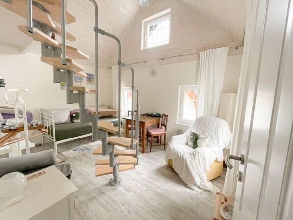 Une pièce compacte et moderne, dotée d’un lit en mezzanine, d’un coin repas et d’un escalier.