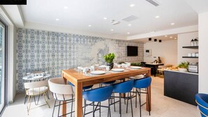 A modern dining area with a wooden table set for four, blue chairs, and a patterned wallpaper. - Central hotel room, with SUPER CLEAN and COMFY BED (Saint Julian's)