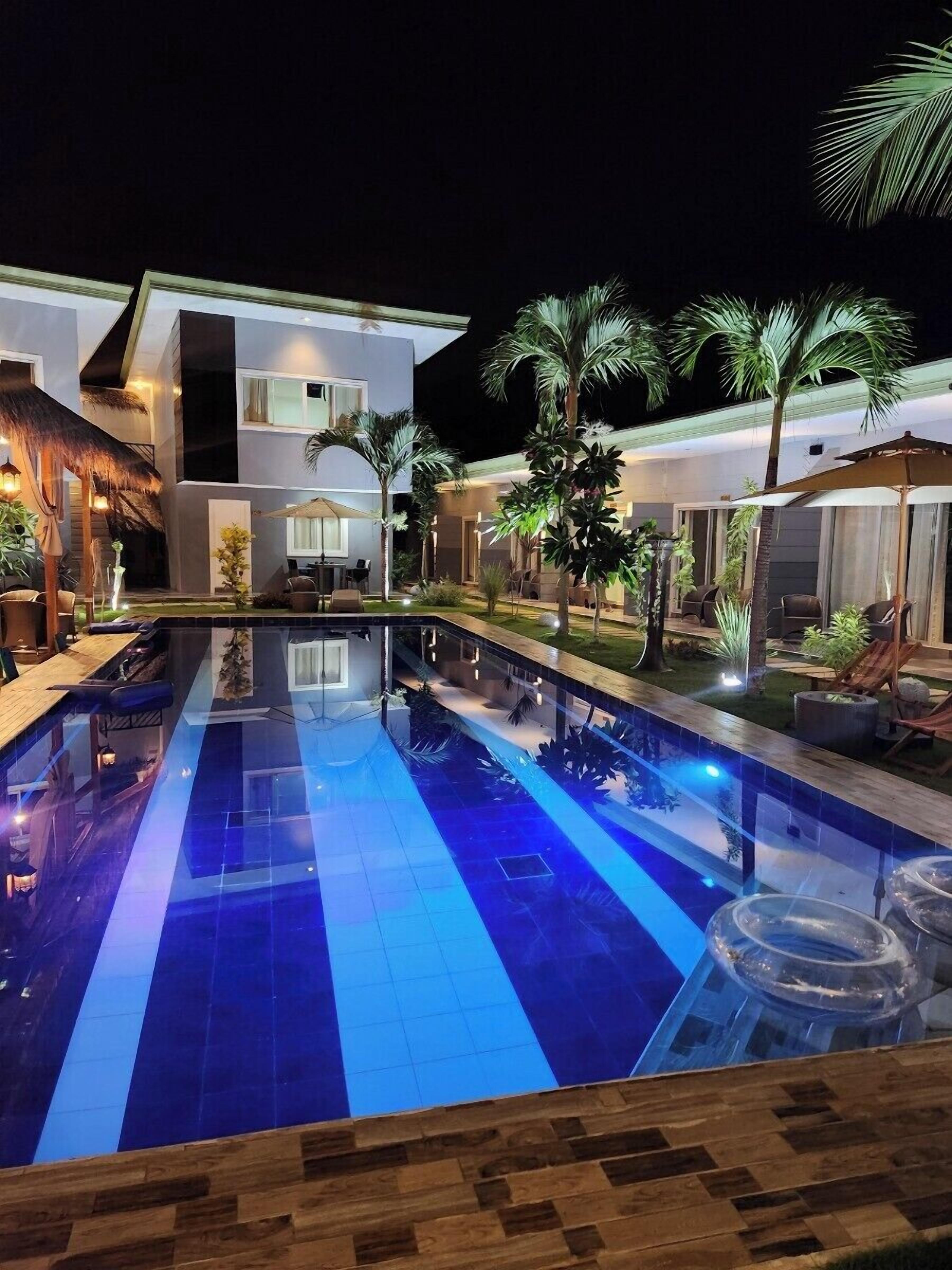 Ein moderner Poolbereich mit klarem, blauem Wasser, Liegestühlen und Palmen.