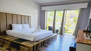 Habitación de hotel moderna con una cama grande, una plataforma de madera y vistas a una piscina y vegetación a través de amplios ventanales.