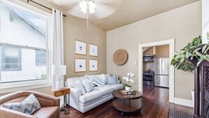 A living room with a sofa, a coffee table, and a fireplace. There is a kitchen visible through an open doorway. - Downtown Heritage Suite | Free Parking (Macon)