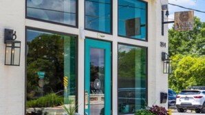 A building with a teal door and large windows, labeled 'Yollah'. - Downtown Heritage Suite | Free Parking (Macon)