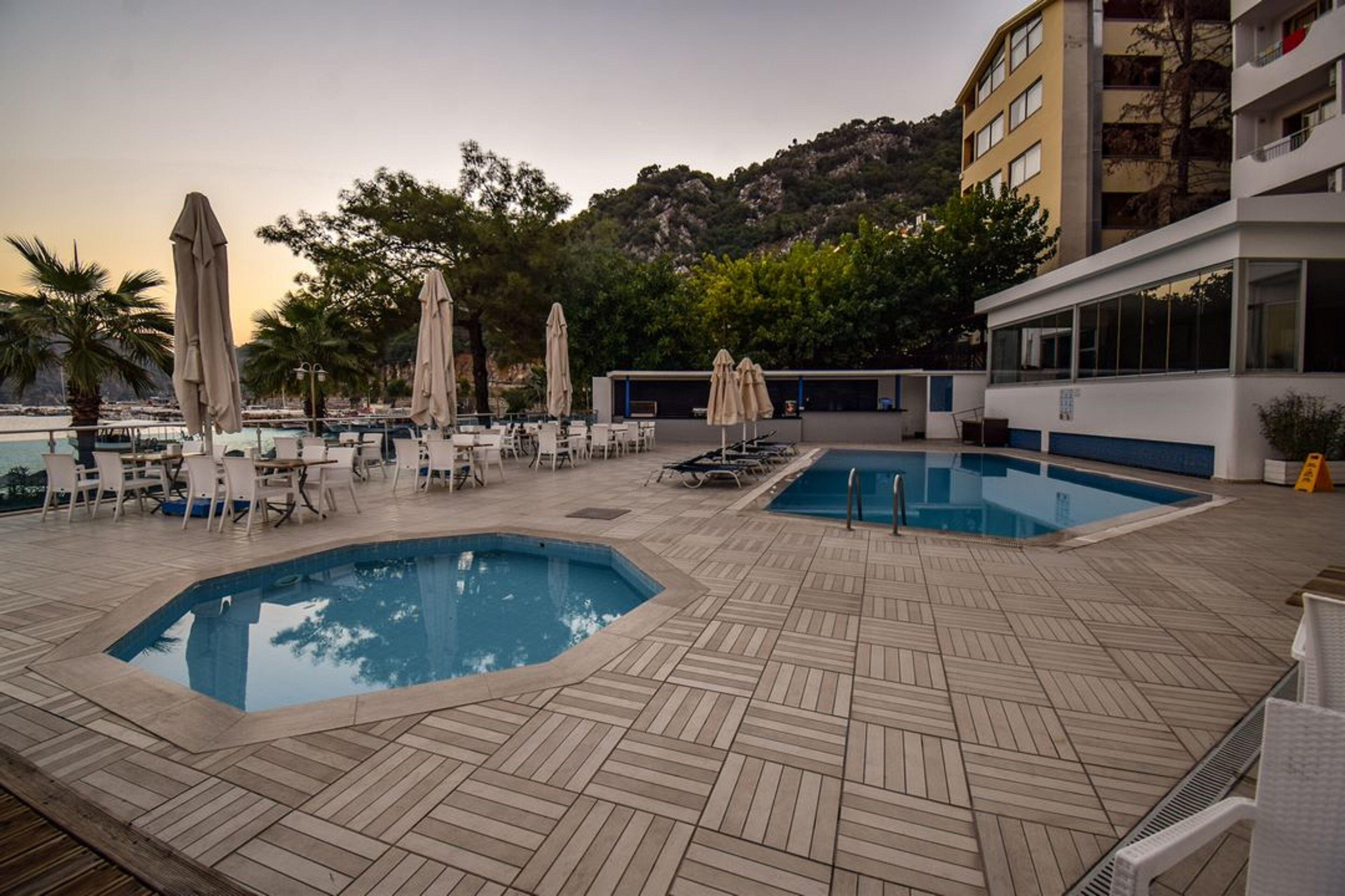 Un espace piscine aménagé sur le toit, comprenant deux piscines, des chaises longues et des parasols.
