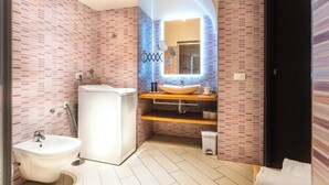 Et badeværelse med en hvid vask, en bidet og et spejl.