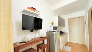 Cocina compacta con televisión integrada, microondas y refrigerador. Cuenta con un pequeño comedor con taburetes y una mesa.