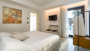 Een moderne hotelkamer met een groot bed, een flatscreen televisie, een zithoek met stoelen en uitzicht op de omgeving.