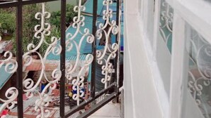 A balcony with ornate metal railings overlooking a residential area with houses and greenery. - Miami Global Hotel (Nairobi)