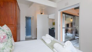 Une chambre d’hôtel avec un lit, une armoire en bois, une salle de bain avec une porte en verre et une vue sur l’extérieur.